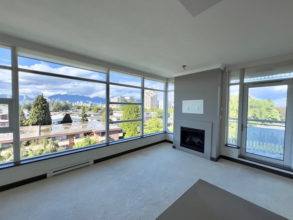 an empty living room with large windows and a fireplace