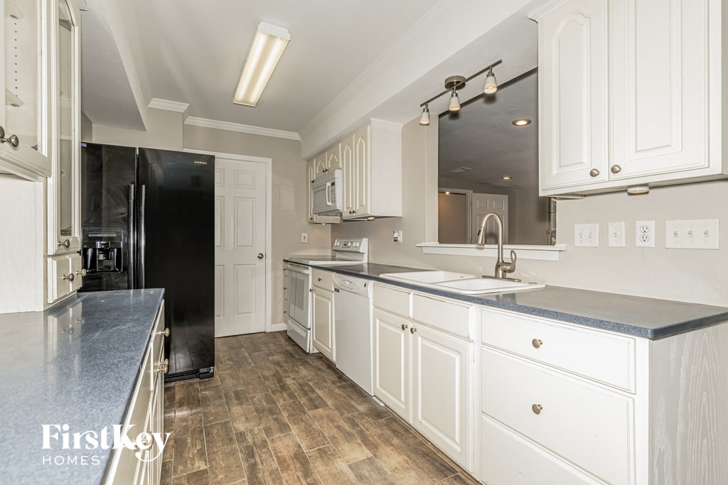 a kitchen with white cabinets and a black refrigerator