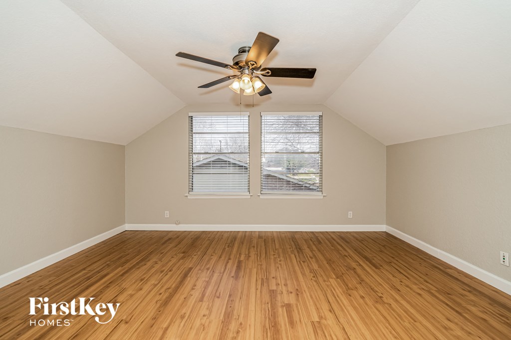 an empty living room with a ceiling fan and two windows