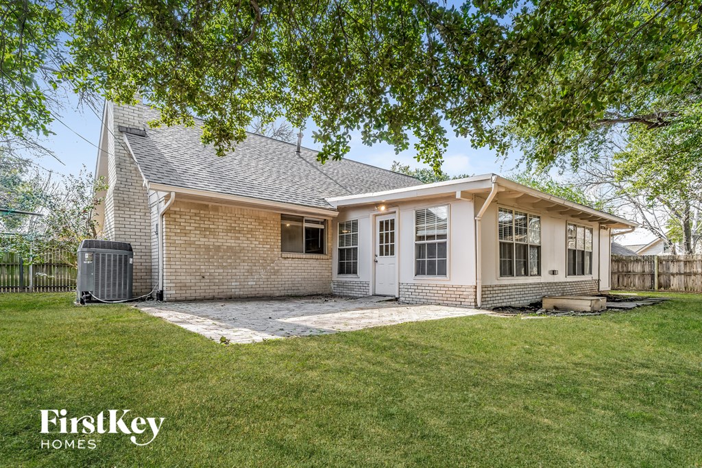 a small brick house with a porch and a grassy yard