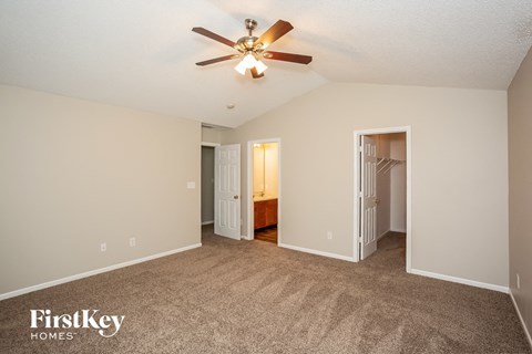 a spacious living room with carpet and a ceiling fan