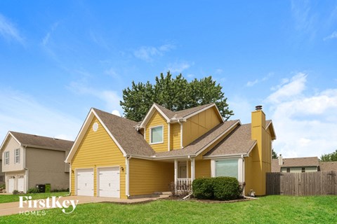 a yellow house with white garage doors and a blue sky
