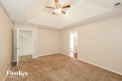 a spacious living room with carpet and a ceiling fan
