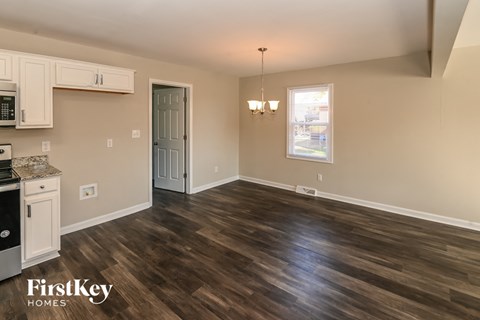 A kitchen with a stove top oven and a dining room table.