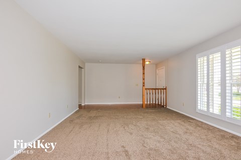 a spacious living room with carpet and large windows