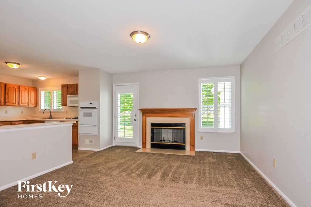 an empty living room with a fireplace and a kitchen
