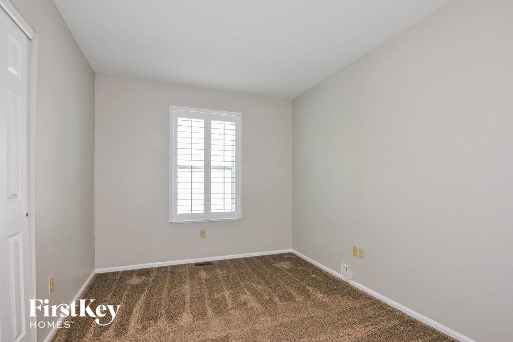 a bedroom with white walls and carpet and a window