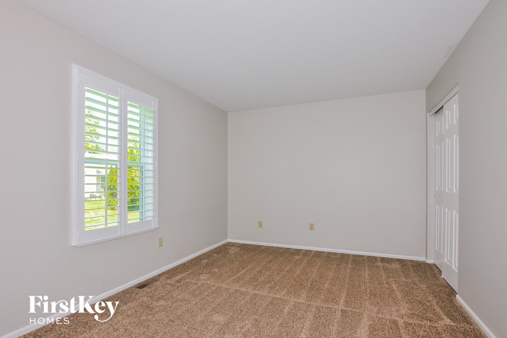 a bedroom with white walls and carpet and a white door