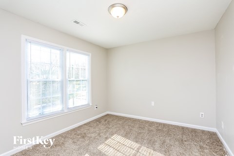 a bedroom with a large window and carpeted floor