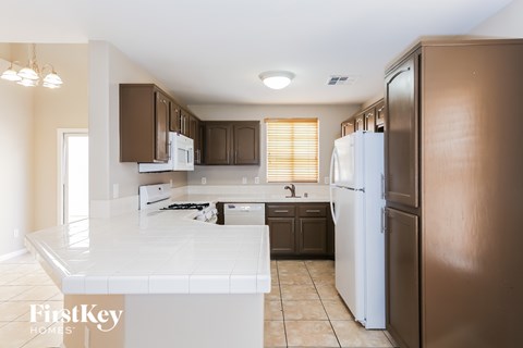 A kitchen with a white counter top and brown cabinets.