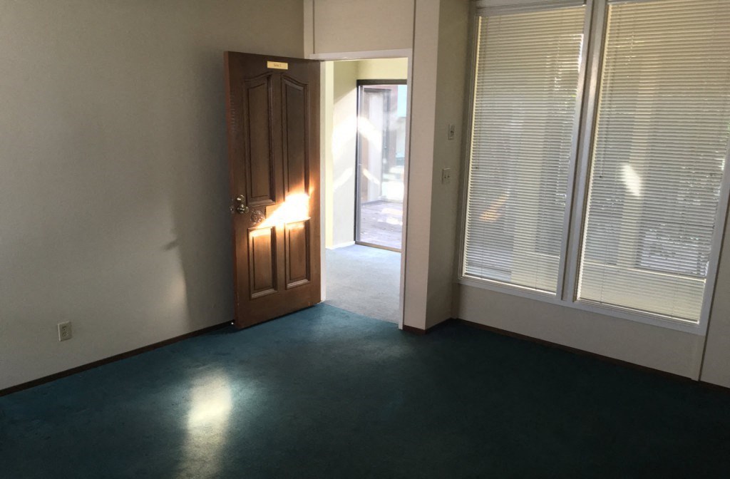 the living room of a house with a door and windows