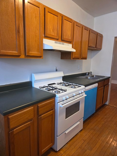 A kitchen with a white stove top oven and blue dishwasher.