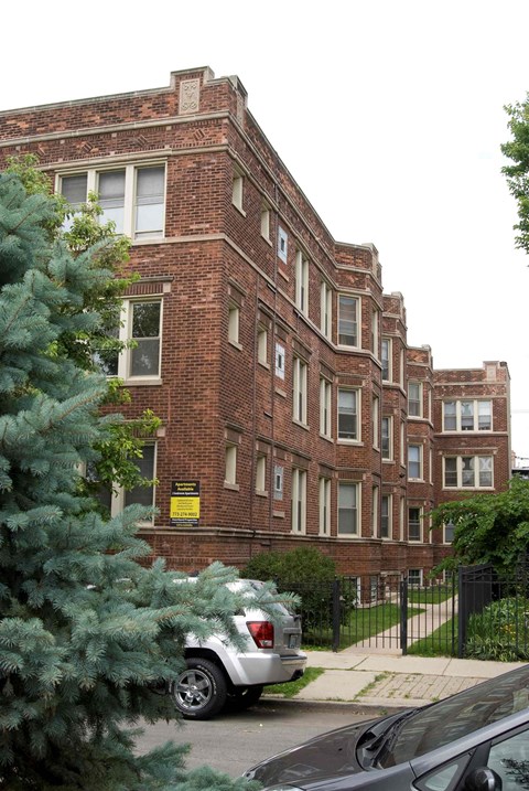 A building with a black fence and a tree in front of it.