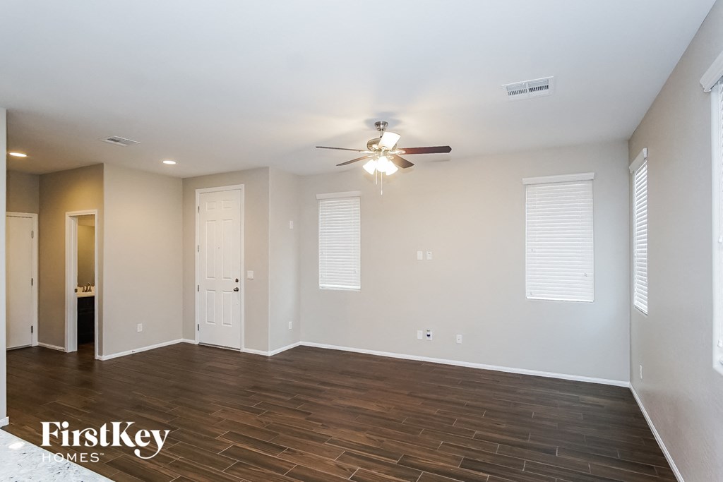 the spacious living room with wood flooring and a ceiling fan