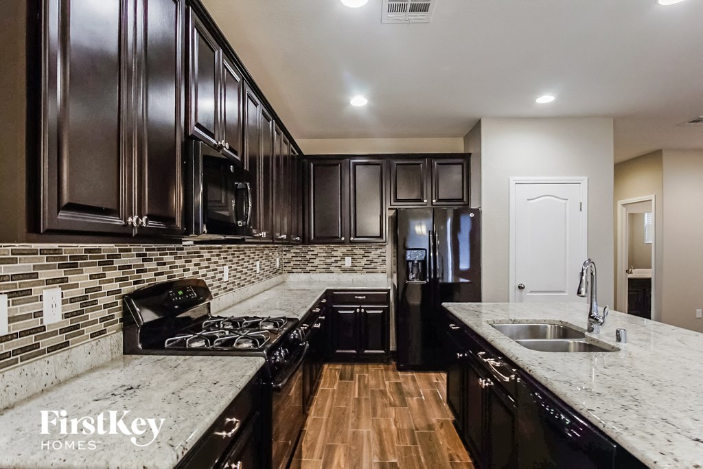 a kitchen with black cabinets and white counter tops and a sink