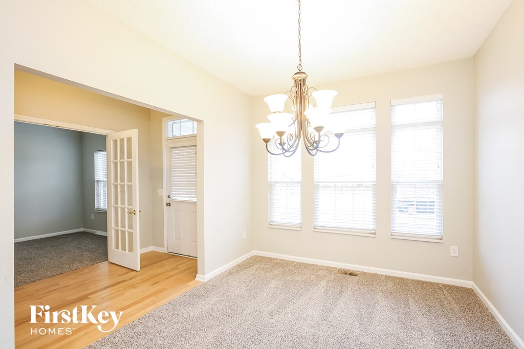 an empty dining room with a chandelier and windows