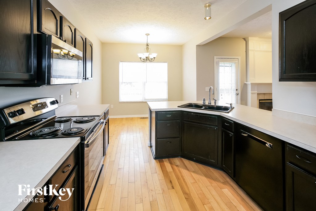 a kitchen with black cabinets and a wood floor