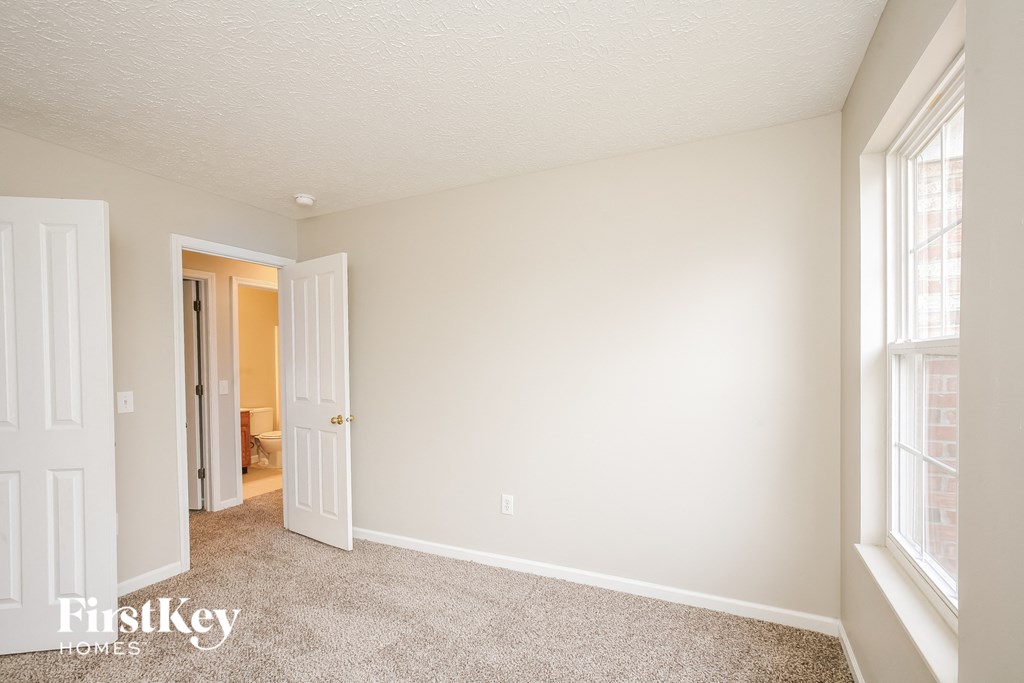 a bedroom with two windows and a door to a hallway