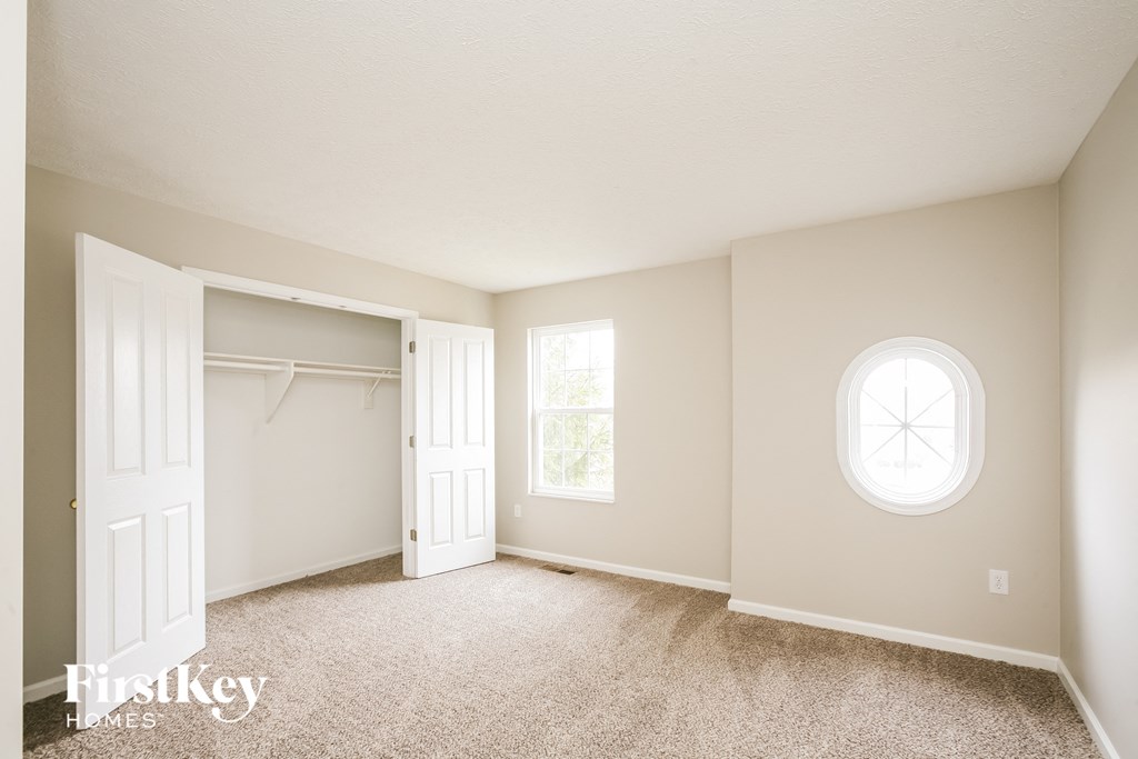 a bedroom with a closet and a white door and a window