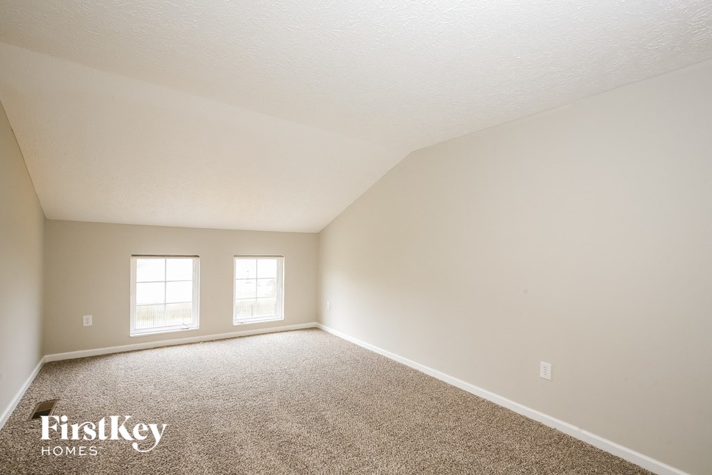 a bedroom with a carpeted floor and two windows