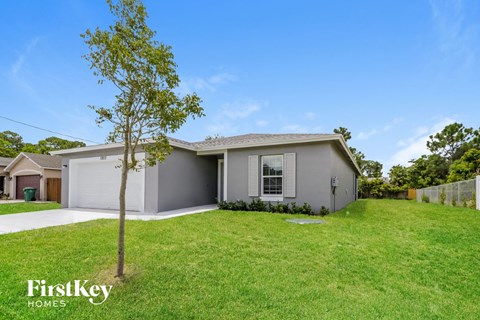 a beige house with a lawn and a tree