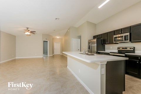 a kitchen and living room with black appliances and a white counter top