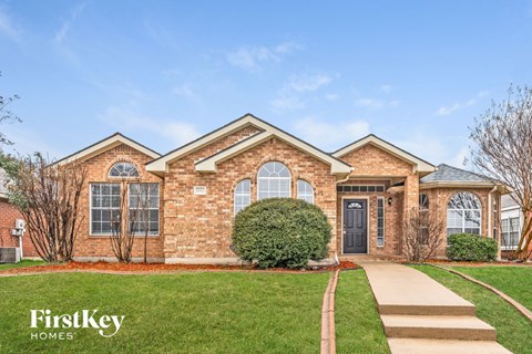 exterior view of a brick house with green grass and a sidewalk