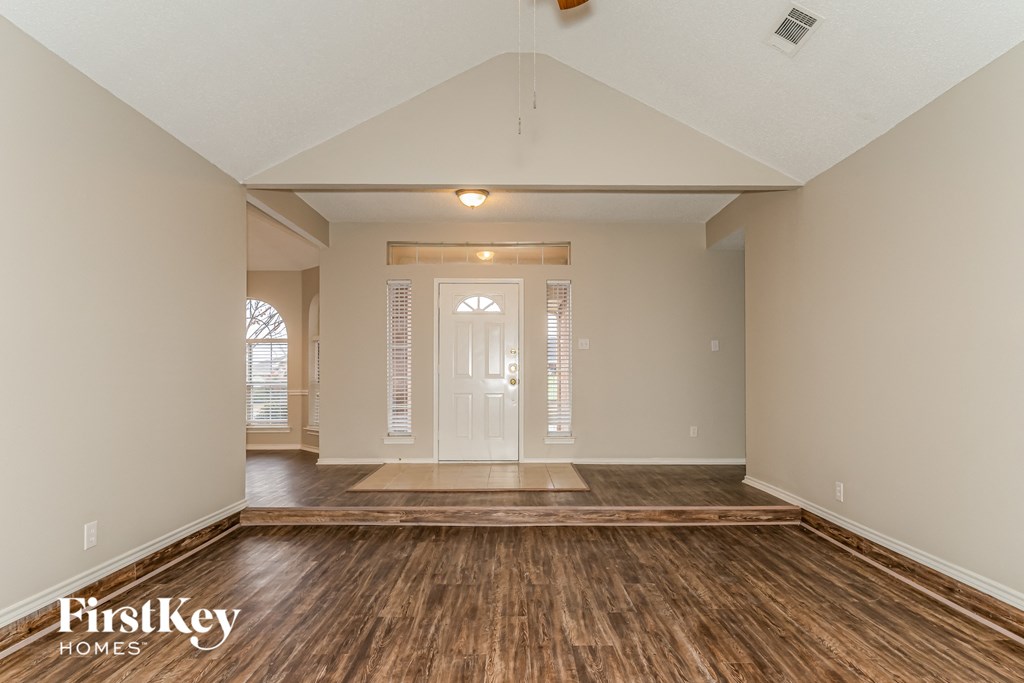 the spacious living room with wood flooring and a white door