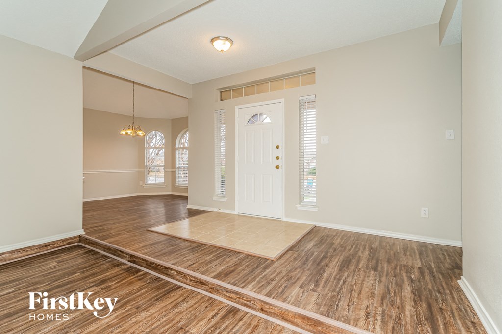 the living room and dining room with wood flooring and a white door