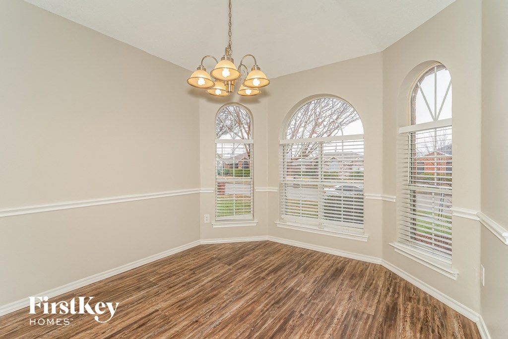 an empty dining room with three windows and a chandelier