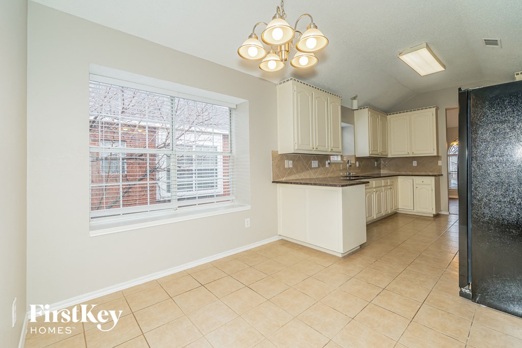 a kitchen with white cabinets and a large window