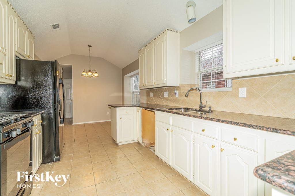 a kitchen with white cabinets and a black refrigerator