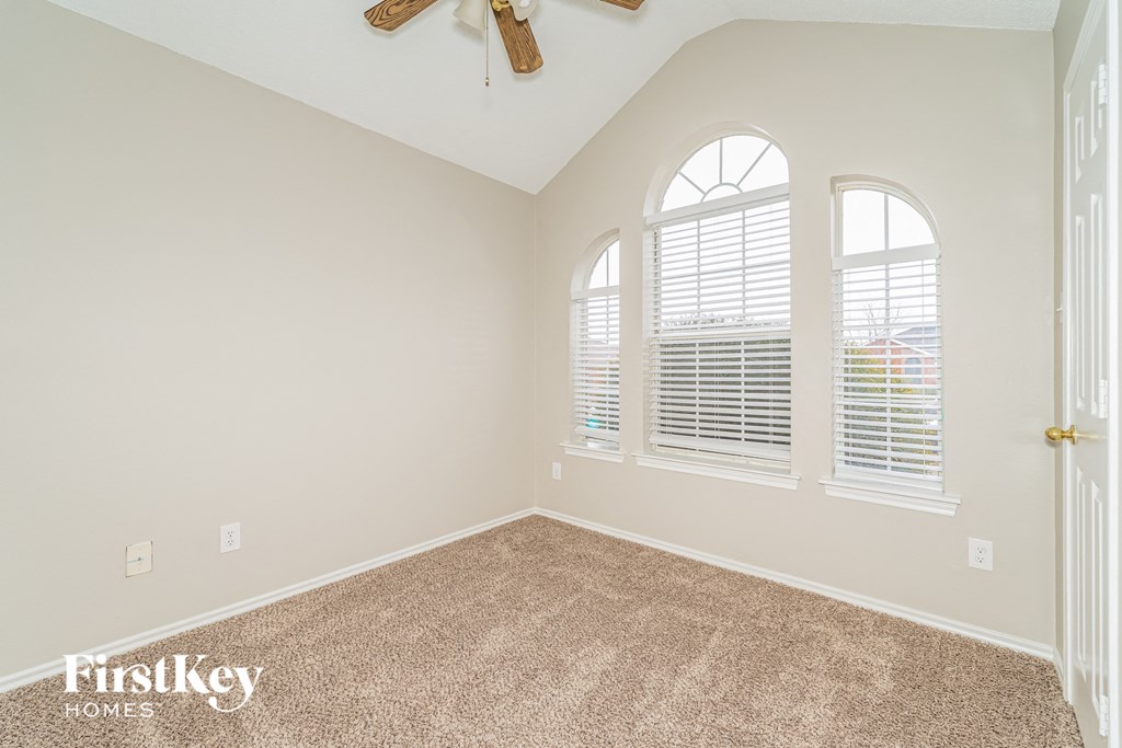 the second bedroom has a large window and carpeted flooring