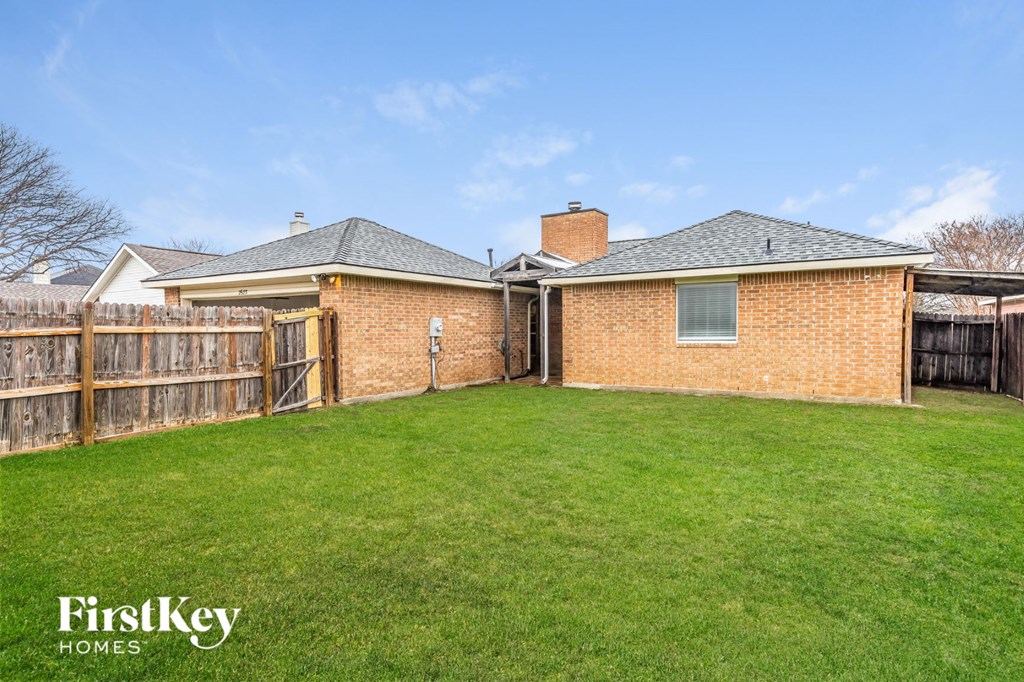 a backyard with a fence and a brick house