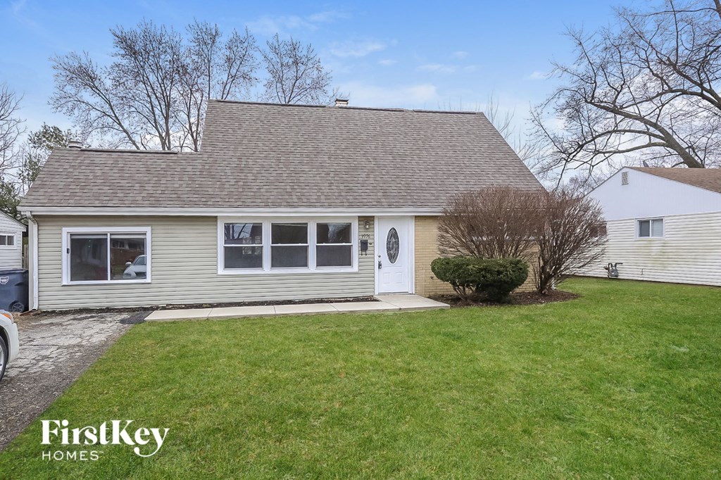 the front of a white house with a lawn and a white door