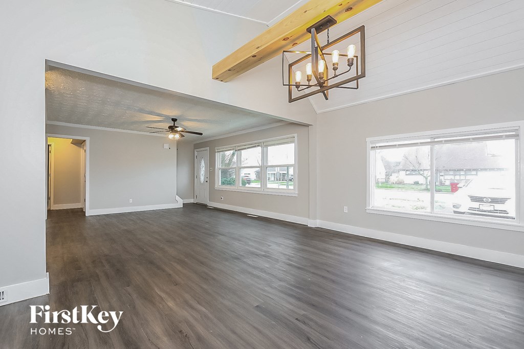 an empty living room with a ceiling fan and a large window