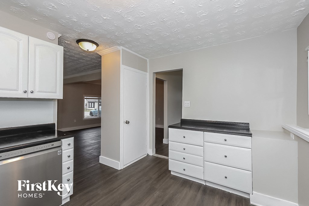 a kitchen with white cabinets and black counter tops