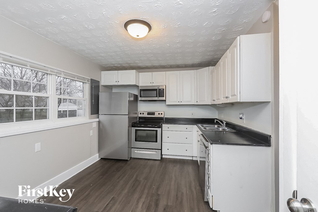a white kitchen with white cabinets and black counter tops