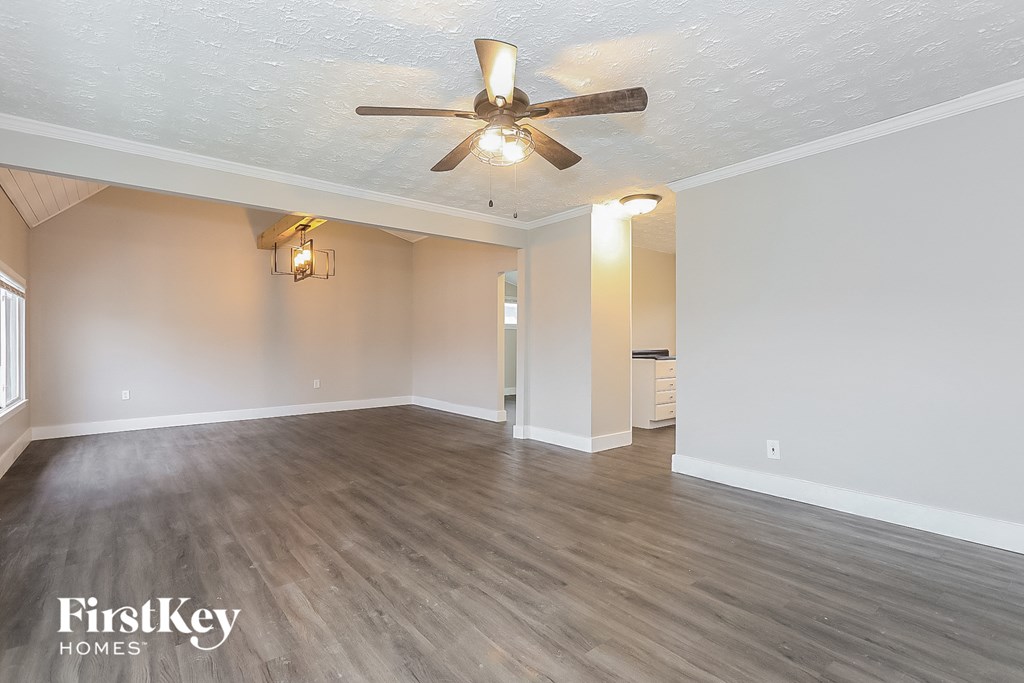 the living room of an empty house with a ceiling fan