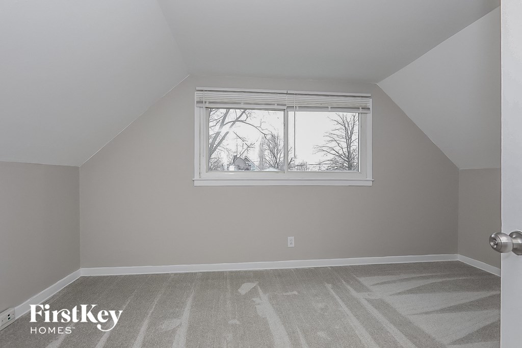 a bedroom with a large window and a gray wall and white floors