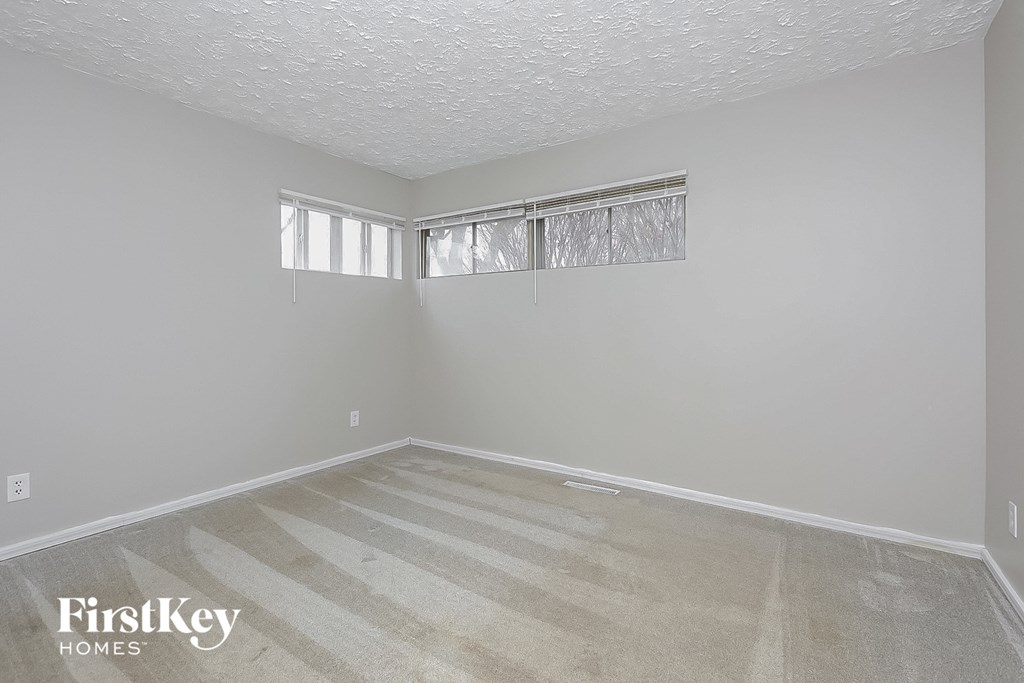 an empty room with a window and white walls and wood floors