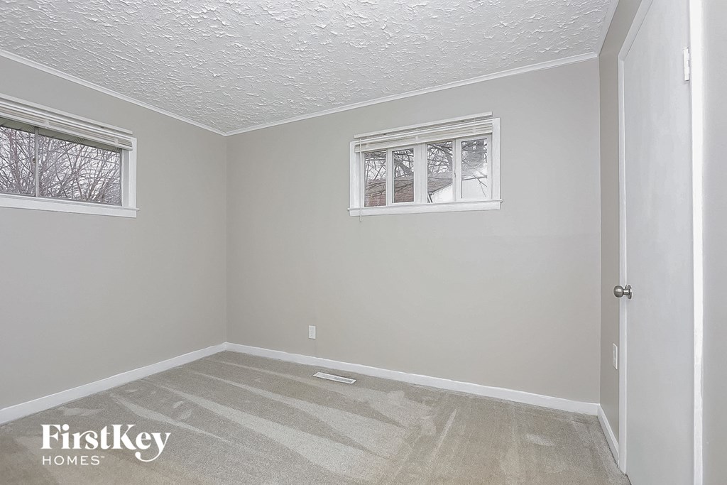 a empty room with white walls and two windows