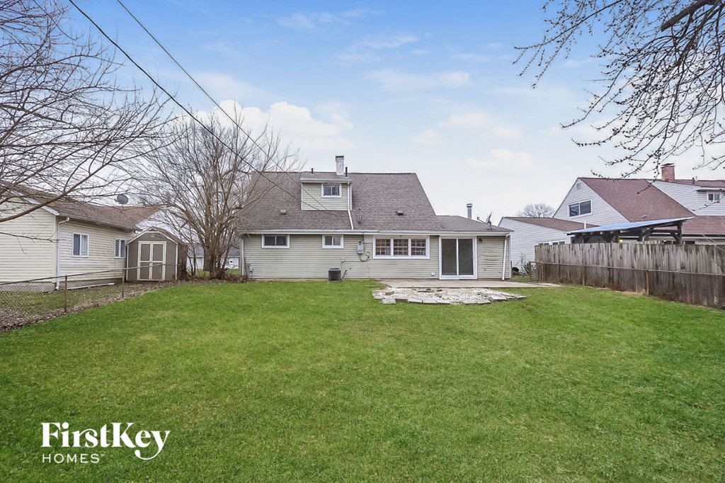 a backyard with a white house and a green lawn