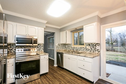 the kitchen of a home with white cabinets and granite counter tops
