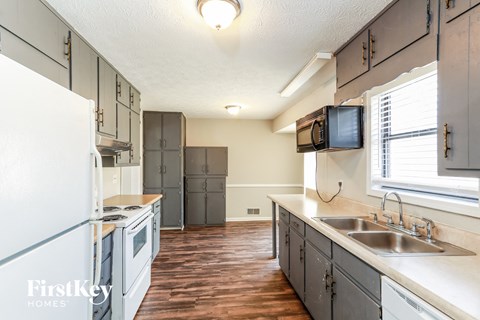 A kitchen with wooden floors and a white refrigerator.