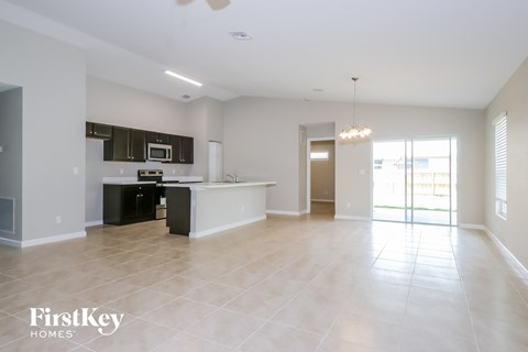 an empty living room with a kitchen and a sliding glass door