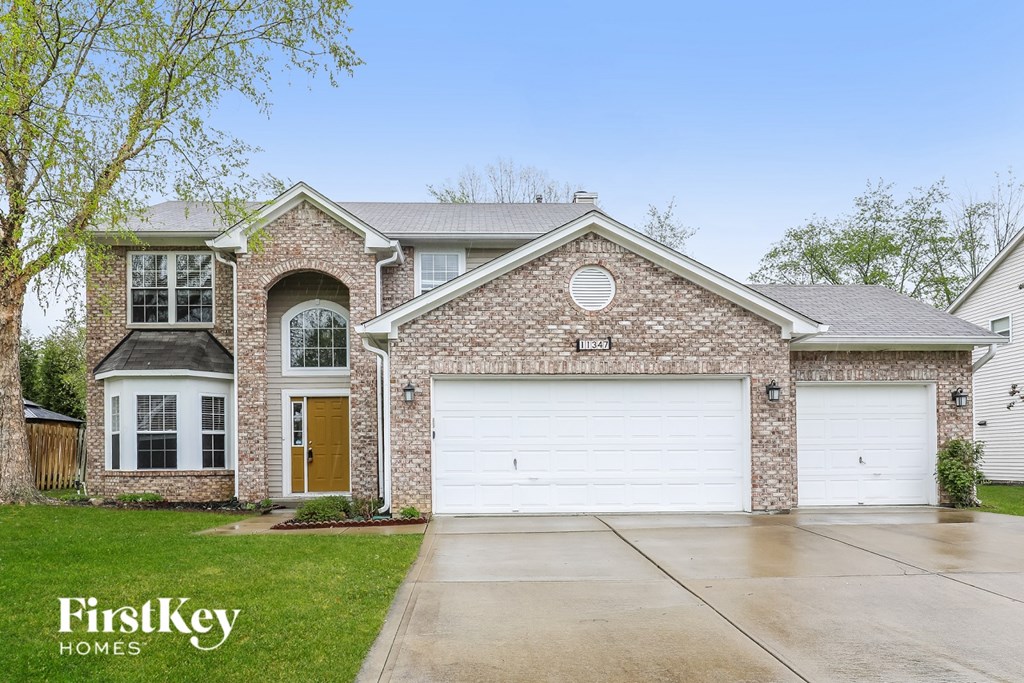 A brick house with a white garage door is for sale.