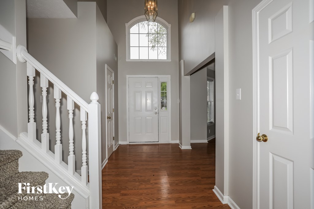 A hallway with a staircase and a chandelier.