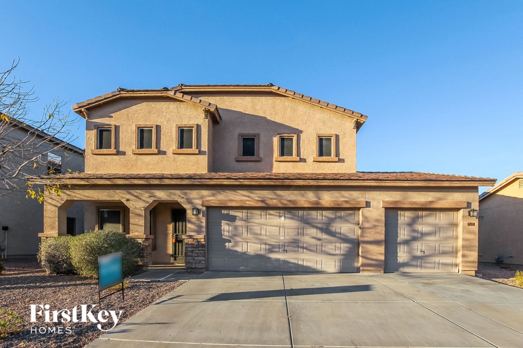 a tan house with a garage and a driveway