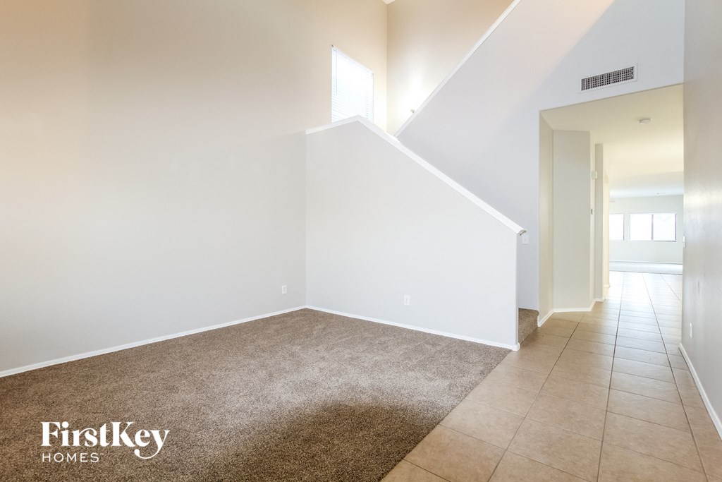 an empty living room with white walls and a beige tile floor